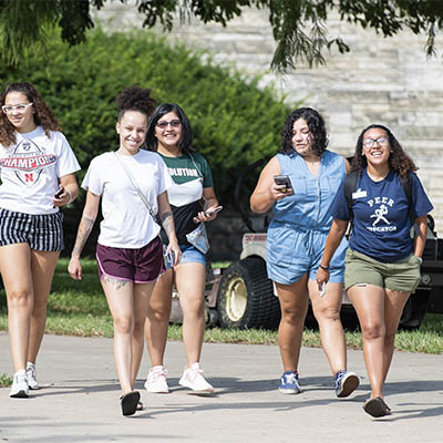 A student leads a group of smiling students on a campus tour